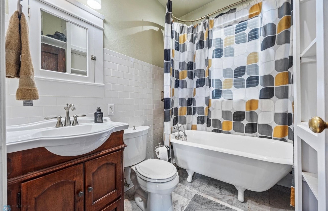 Bathroom — cherry wood vanity with clawfoot tub and subway tile