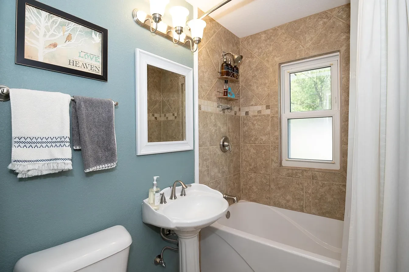 Bathroom — teal walls wide view with dual vessel sinks and decorative mirror