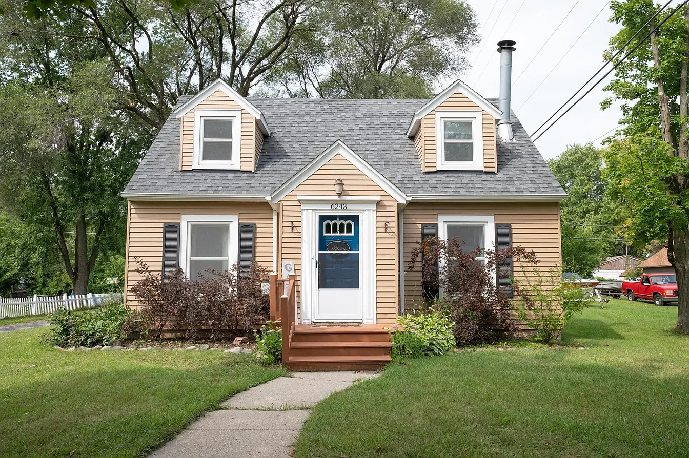 Exterior — tan cape cod front with blue door and landscaping