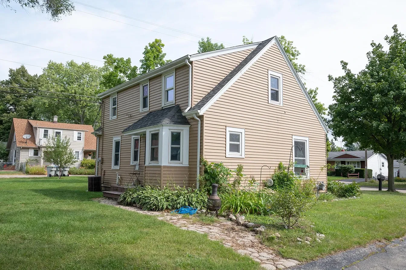 Exterior — tan two-story home rear view with garden, summer