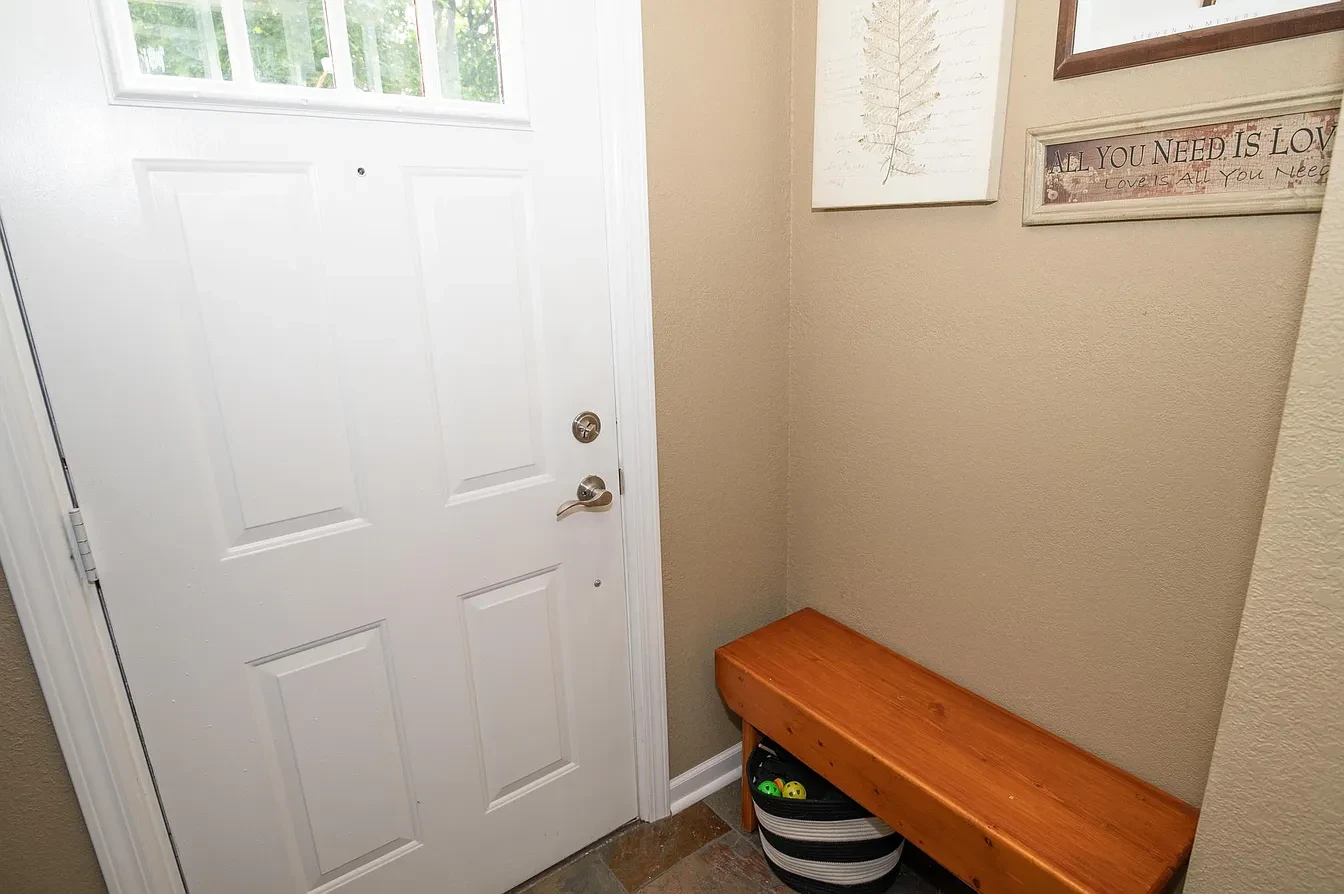 Entryway with white door and wood bench