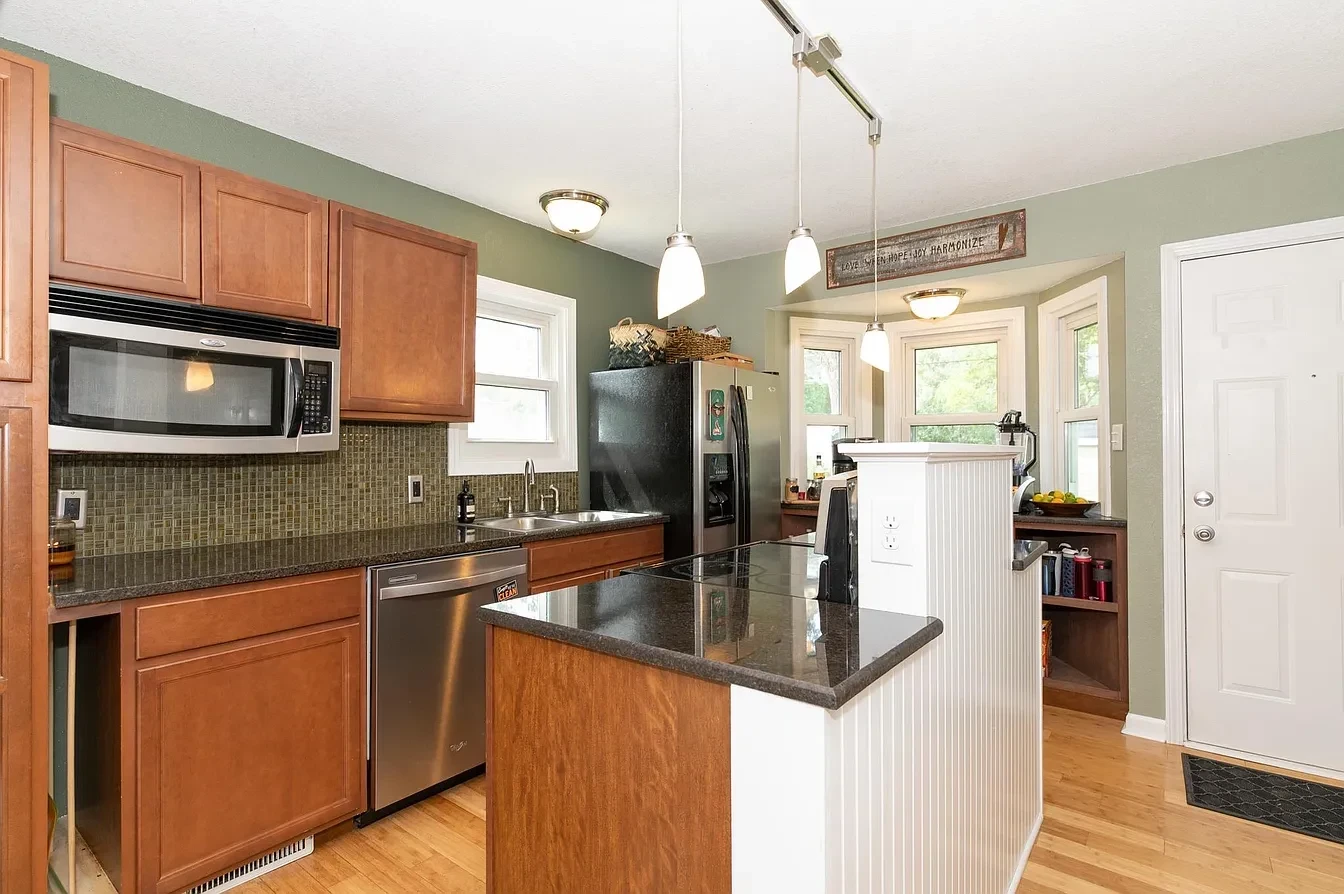 Kitchen — warm cherry wood cabinetry with sage walls